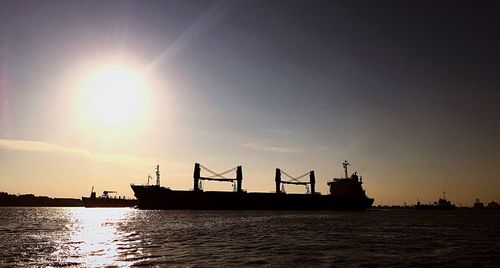 Silhouette ship in sea against sky during sunset