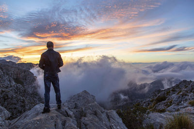 Rear view of man standing on mountain against sky