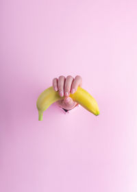 Close-up of hand holding apple against white background