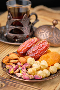 Dates, dried apricots, nut mix and tea in traditional arabian style brass holder.  ramadan kareem