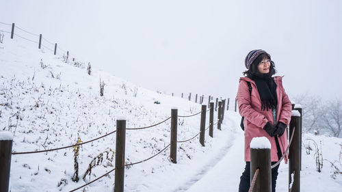 Portrait of young woman walking on snow covered landscape