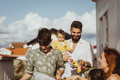 Happy father carrying daughter while family smiling by cabin