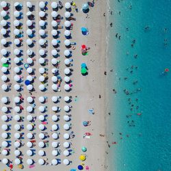 Directly above shot of parasols and people at beach during sunny day