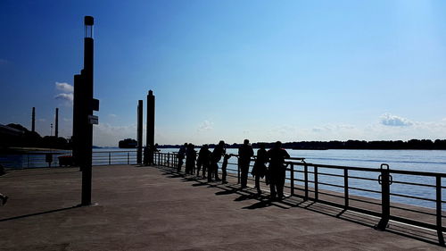 Silhouette people standing on pier by sea against clear sky