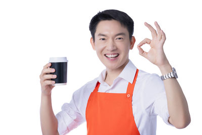 Portrait of smiling young man holding glass over white background