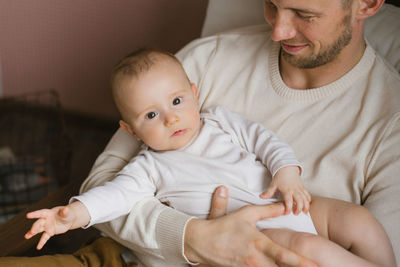 A caucasian father holds his baby son in his arms. happy fatherhood and family