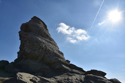 Low angle view of rock formation against sky on sunny day