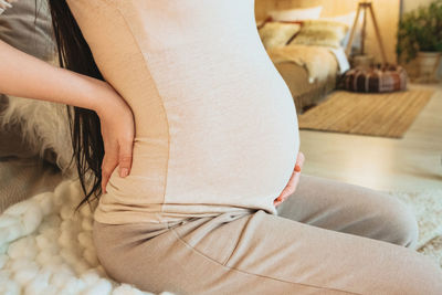 Midsection of woman lying on bed at home