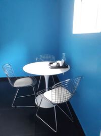 Empty chairs and table against wall