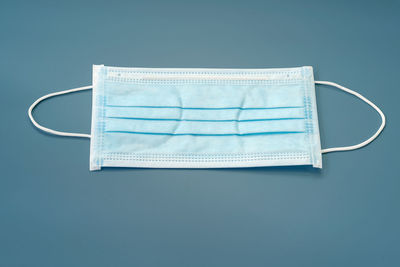 High angle view of surgical mask on blue background