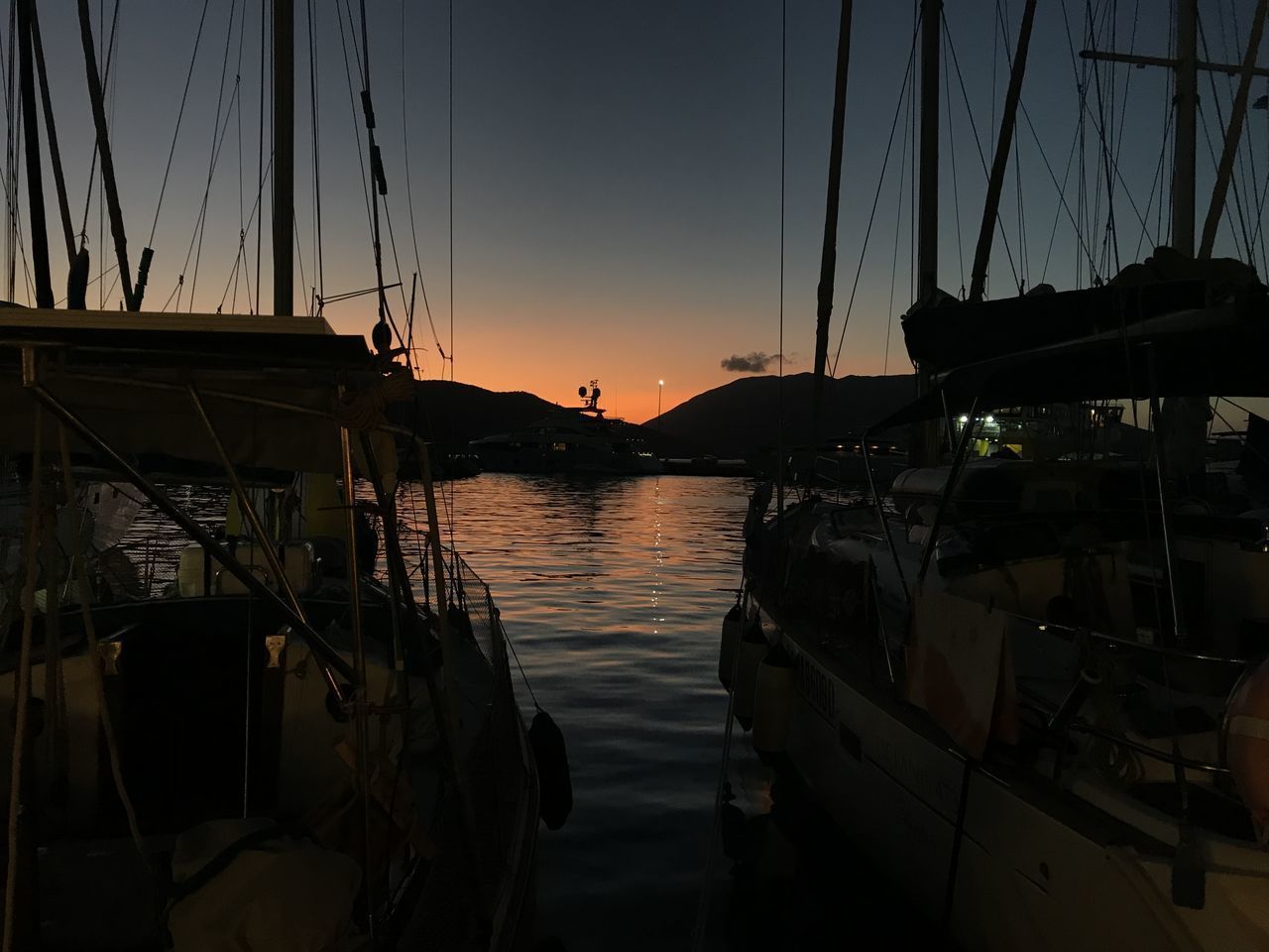 BOATS MOORED AT HARBOR AT SUNSET