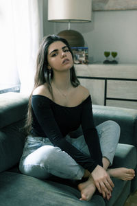 Young woman sitting on sofa at home