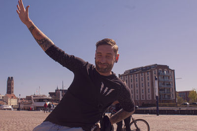 Portrait of young man in city against clear sky