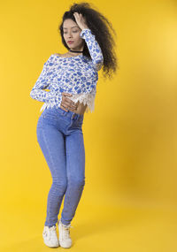 Portrait of woman standing against yellow background