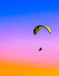 Low angle view of person paragliding against sky during sunset