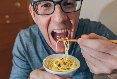 Portrait of man eating noodles and worms in restaurant