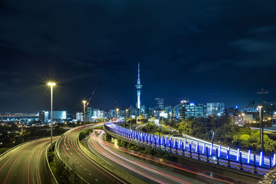 Road leading towards sky tower against sky in illuminated city at night