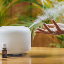 Woman enjoying aroma therapy steam scent from home essential oil diffuser or air humidifier.