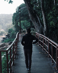 Rear view of man standing on footbridge