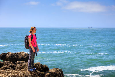 Rear view of woman standing by sea against sky