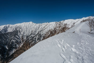 Scenic view of snowcapped mountains against clear blue sky