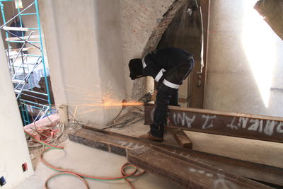 Worker grinding metal in building