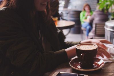 Midsection of woman with coffee cup in restaurant