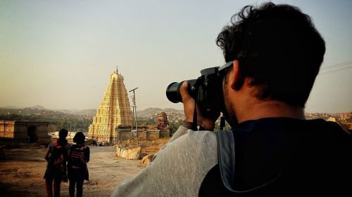 Rear view of man photographing temple