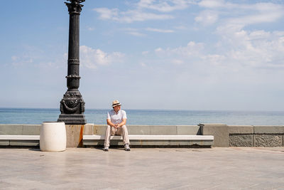 Summer travel and vacation. young man sitting on the bench by the sea, enjoying the view