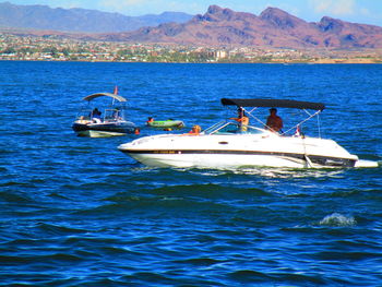 People in boat on sea against mountain