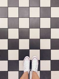 Low section of man standing on checked patterned floor