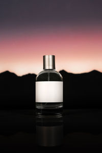 A plain perfume bottle with a sunset background