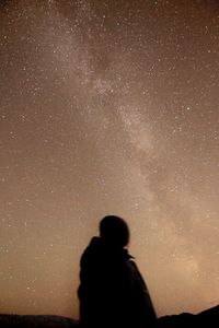 Rear view of silhouette woman against sky at night