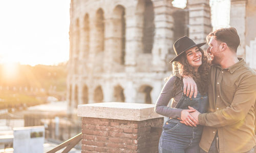 Romantic young couple standing against coliseum