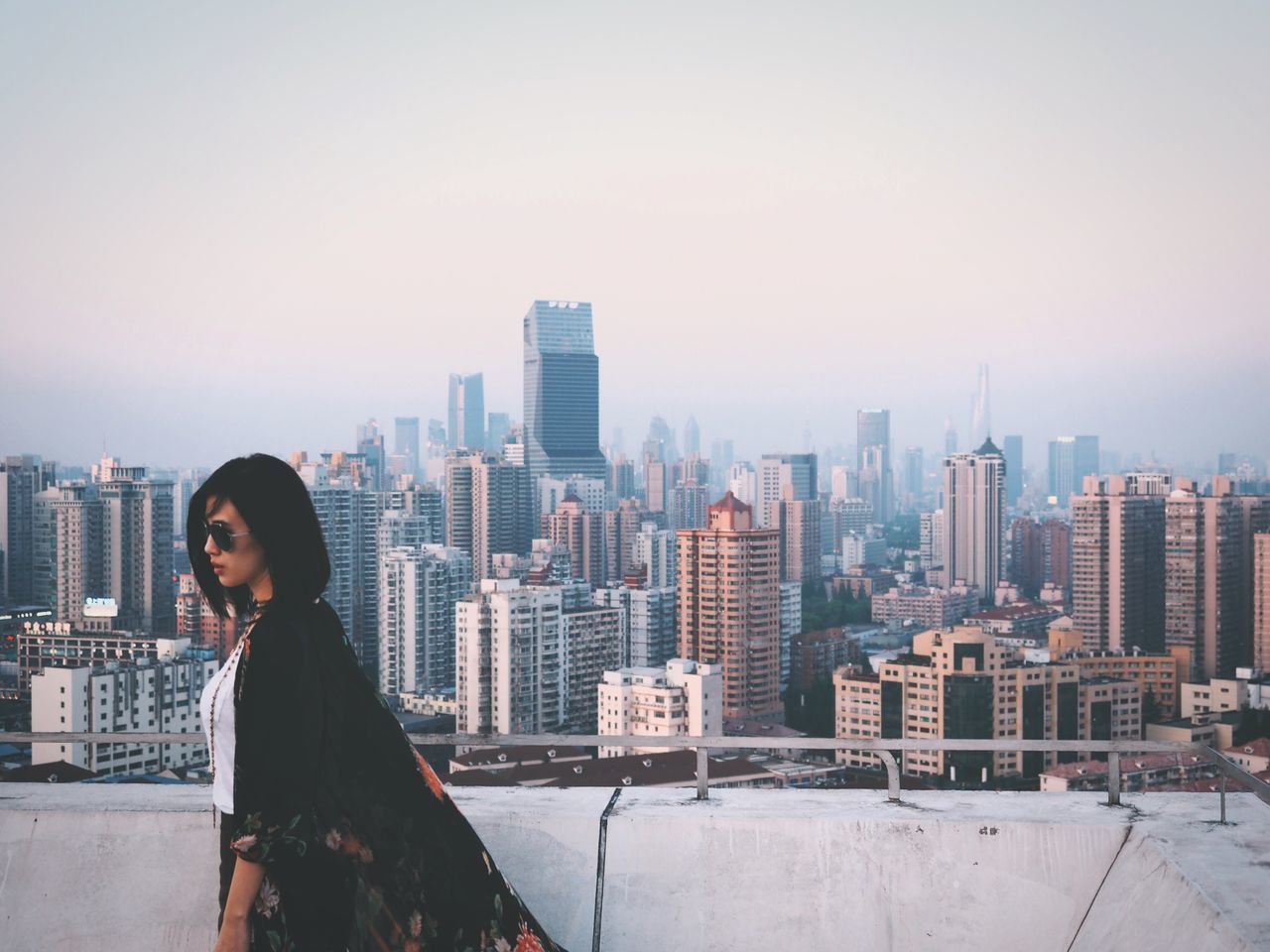 building exterior, city, architecture, built structure, cityscape, lifestyles, skyscraper, leisure activity, standing, clear sky, young adult, casual clothing, city life, looking at view, tower, tall - high, sky, waist up