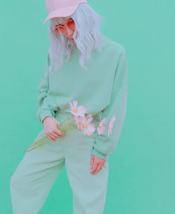 Portrait of woman with pink flowers against colored background