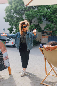 Young woman wearing sunglasses standing by car