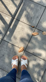 Low section of woman standing on tiled floor outdoors