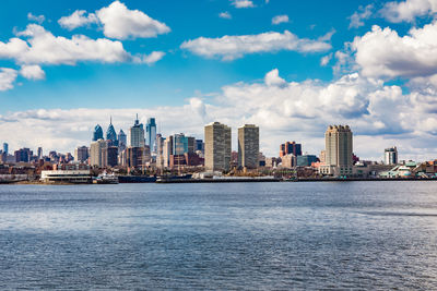 Sea by modern buildings in city against sky