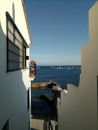 Buildings by sea against clear blue sky