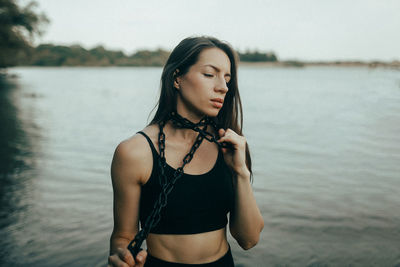 Portrait of young woman standing against lake