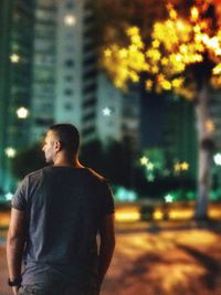 Man looking at illuminated city street