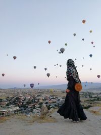 Rear view of woman looking at hot air balloons against sky