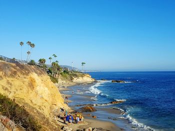 People on beach against clear blue sky