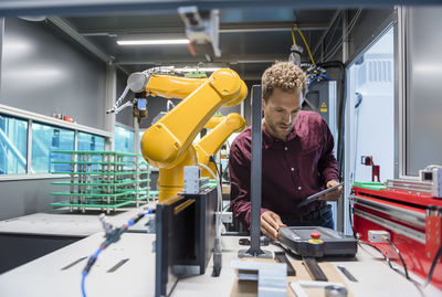 Businessman checking industrial robot in high tech company