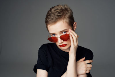 Portrait of boy wearing sunglasses against gray background