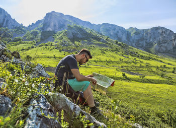 Woman sitting on field against mountain range