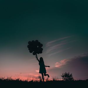 Silhouette of young girl holding balloons