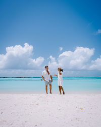 Friends standing on beach against sea