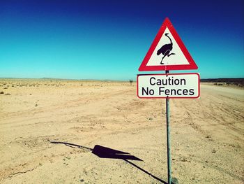 Road sign on desert against clear blue sky